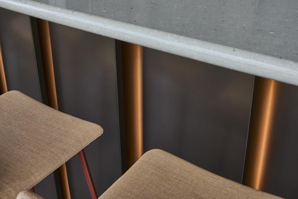 Hochwertige Details im Innenausbau: Barhocker und Thekenfront Detailaufnahme einer modernen Theke mit Stoff-Barhockern und Kupferakzenten