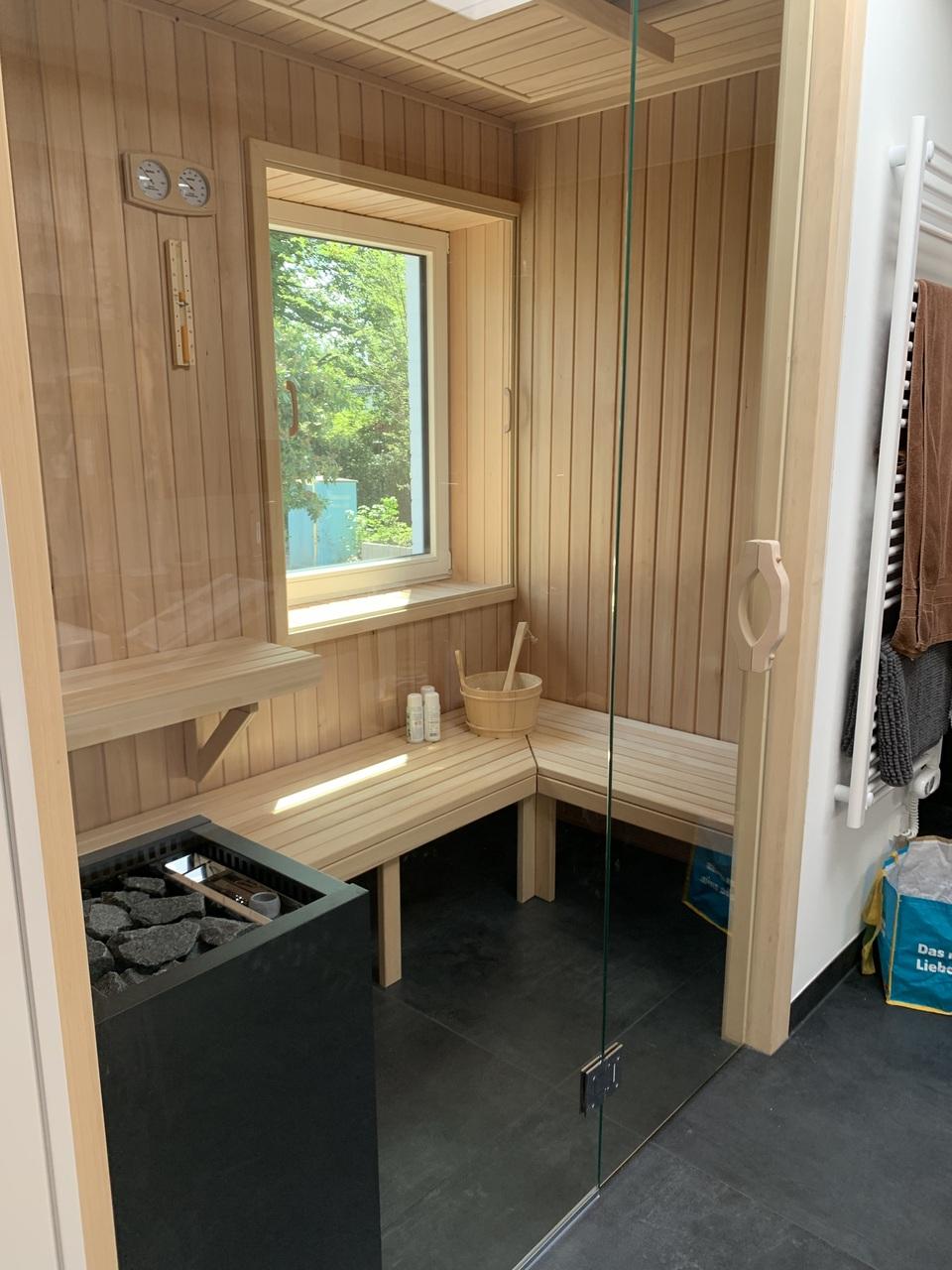 Maßgefertigte Sauna mit Holzverkleidung und Glasfront Eine maßgefertigte Sauna mit Holzverkleidung, Glasfront und einer Sitzbank. Ein Fenster sorgt für natürlichen Lichteinfall. Die Sauna ist modern gestaltet. Maßgefertigte Sauna.