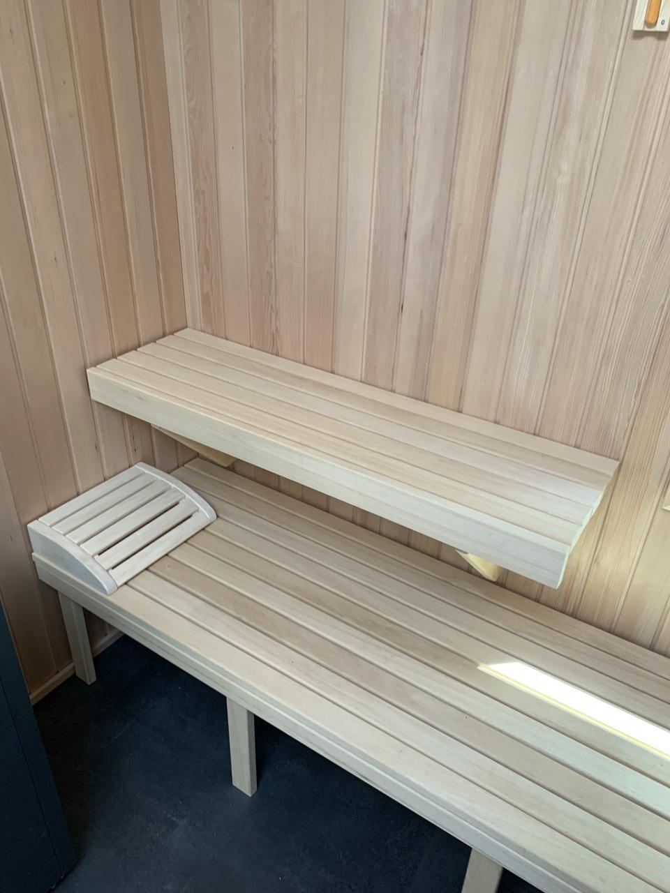 Sitzbänke in maßgefertigter Sauna aus Holz Zwei schlichte Holzbänke in einer maßgefertigten Sauna mit Holzverkleidung. Die Bänke bieten verschiedene Sitzhöhen für optimalen Komfort. Maßgefertigte Sauna.