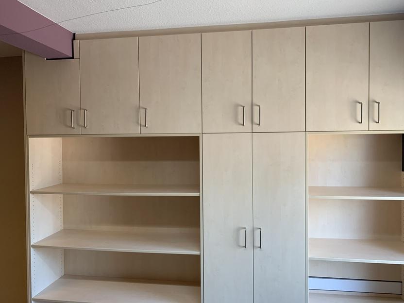 Maßgefertigter Einbauschrank mit offenen Regalen und Schränken Ein maßgefertigter Einbauschrank aus hellem Holz mit hohen Schranktüren und offenen Regalfächern, die zusätzlichen Stauraum bieten. Der Schrank ist perfekt in den Raum integriert. Schrank nach Maß.