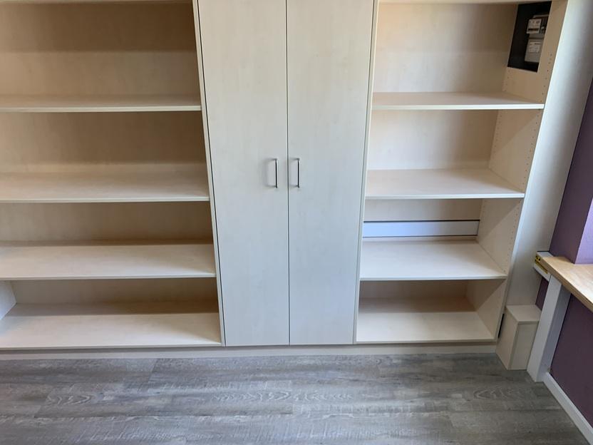 Einbauschrank mit offenen Regalen und Technikfach Maßgefertigter Schrank mit hellem Holzdekor, zwei Türen in der Mitte, offenen Regalböden an den Seiten und integriertem Zugang zum Sicherungskasten