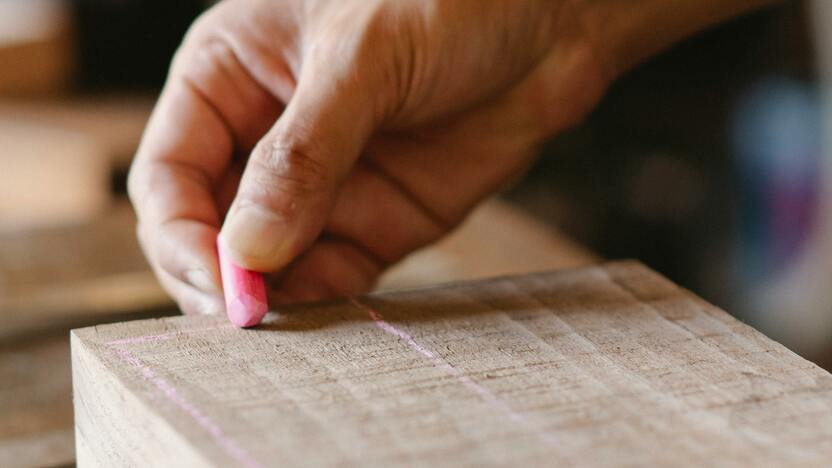 Markieren auf Holz für maßgefertigte Möbel Eine Hand zeichnet mit Kreide präzise Markierungen auf ein Holzstück, um Möbel nach Maß anzufertigen. Das Bild zeigt den ersten Schritt der Holzbearbeitung im Möbelbau.